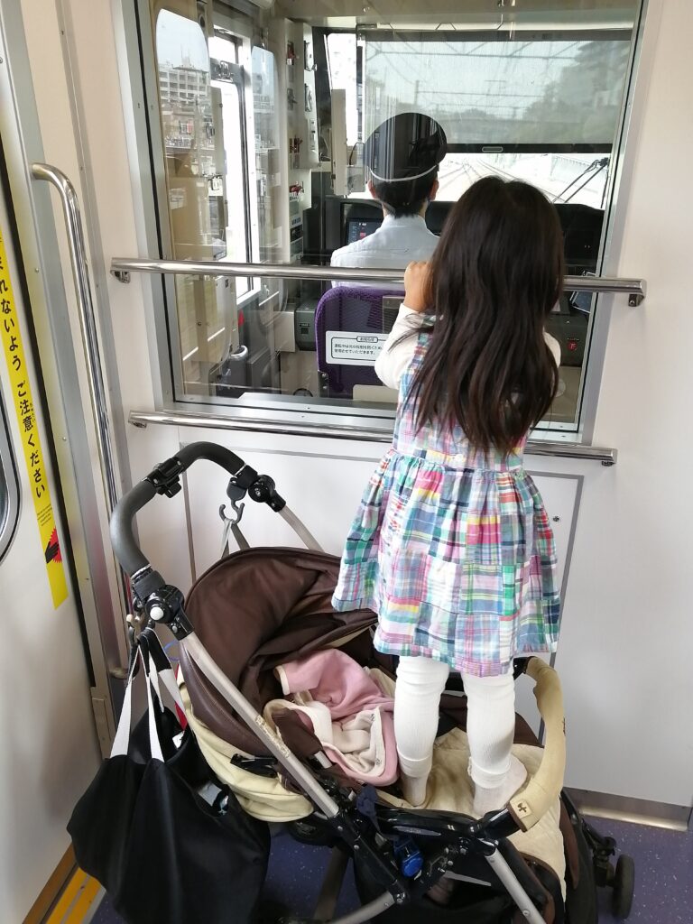 ベビーカーの上に乗って電車の運転席を見ている写真