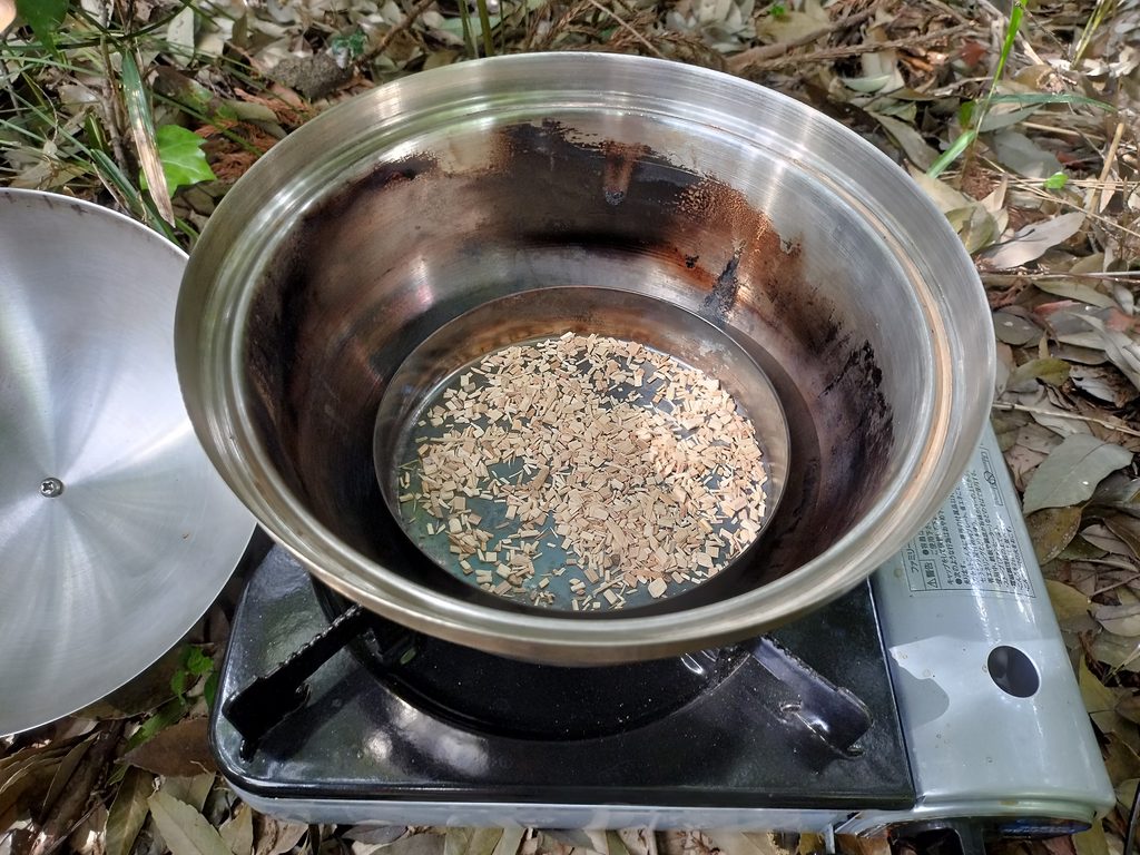 カセットコンロに置いたコンパクトスモーカーにスモークチップを入れたところ