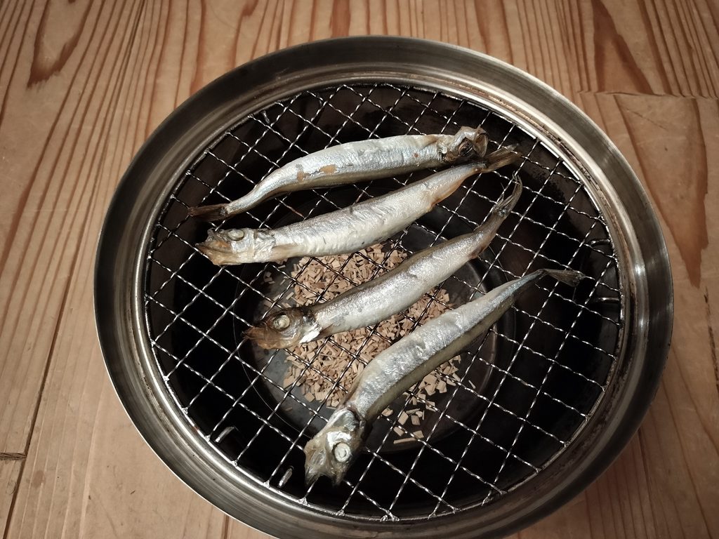 生のししゃもを網にのせて燻製しているところ